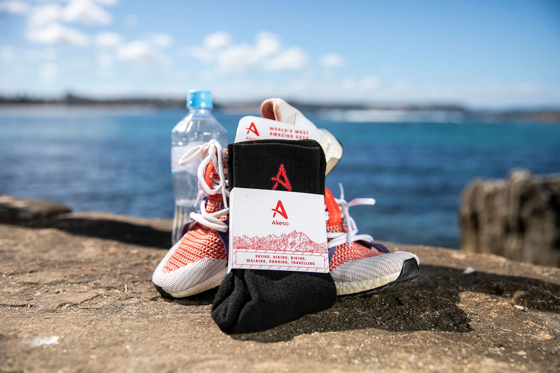 Akeso socks leaning against running shoes with water bottle